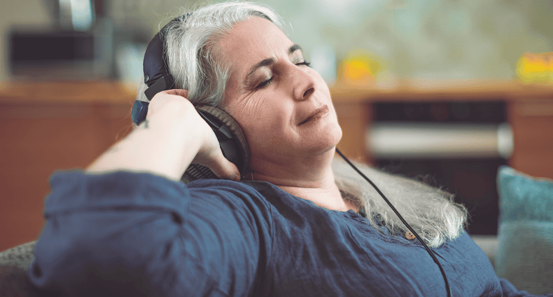 Gray-haired woman enjoying music with headphones