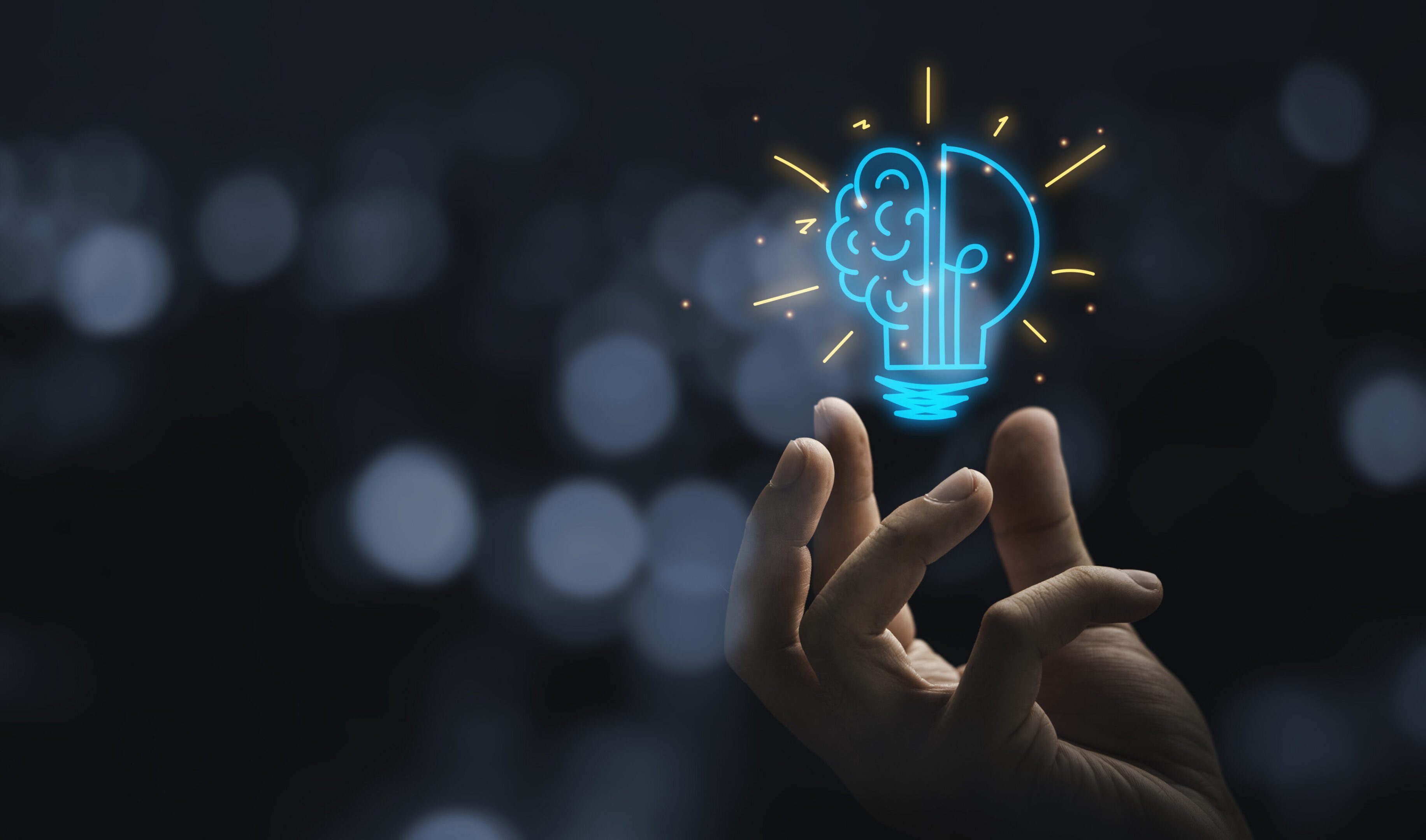 Hand holding a glowing brain lightbulb.